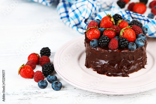 Tasty chocolate cake with different berries, on wooden table
