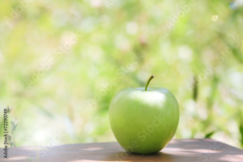 Juicy green apple on table, outdoors © Africa Studio