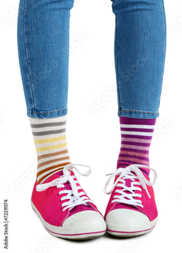 Female legs in colorful socks and sneakers isolated on white