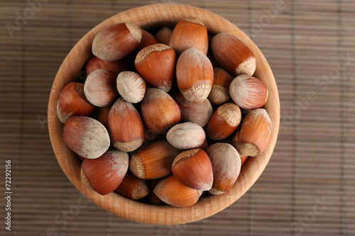 Hazelnuts in wooden bowl on bamboo mat background
