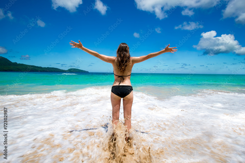 Young girl in bikini with raised arms tropical sea beach