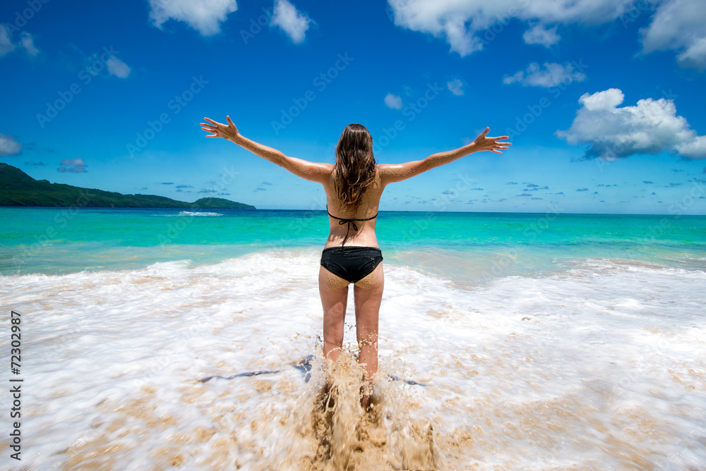 Young girl in bikini with raised arms tropical sea beach Young girl in bikini with raised arms tropical sea beach