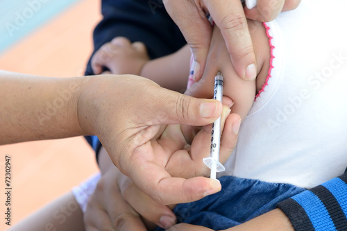 Doctor giving a child an intramuscular injection in arm  shallow