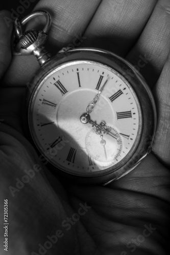 old pocket watch in black and white in human hand