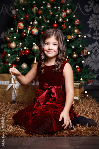 Beautiful little girl ringing a bell at Christmas