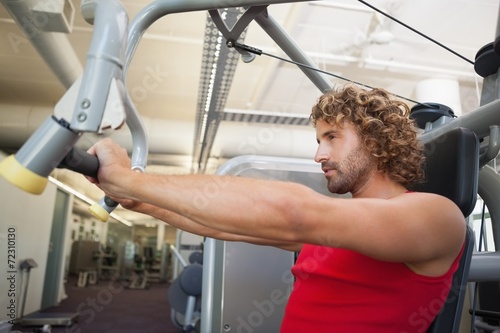 Side view of man working on fitness machine at gym