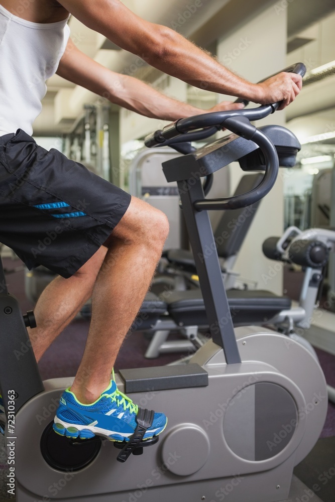 Cropped man working out on exercise bike at gym Cropped man working out on exercise bike at gym