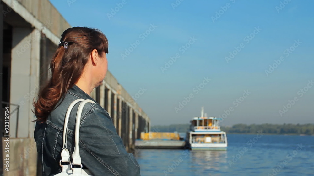pretty woman watching on river, boat at background in defocus