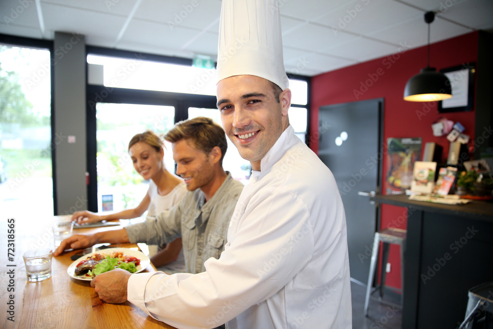 Obraz premium Smiling chef serving customers in restaurant