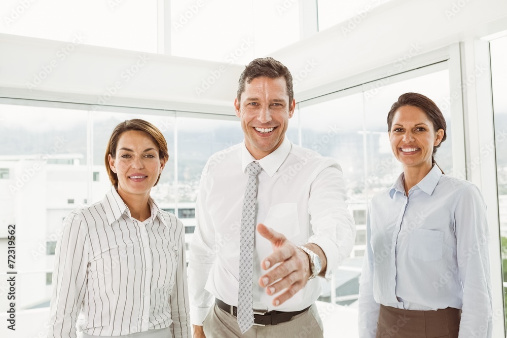 Businessman with colleagues offering handshake at office Businessman with colleagues offering handshake at office