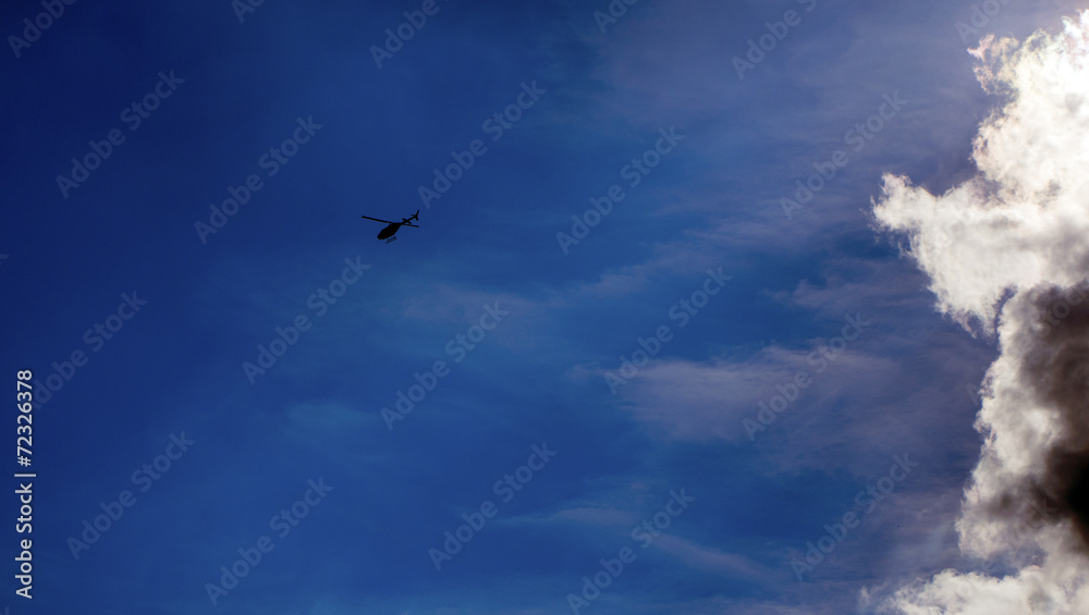 Helicopter flying away from the clouds