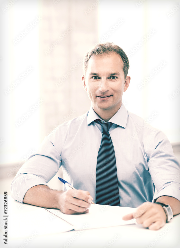 handsome businessman writing in notebook handsome businessman writing in notebook