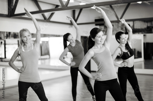 group of smiling people stretching in the gym