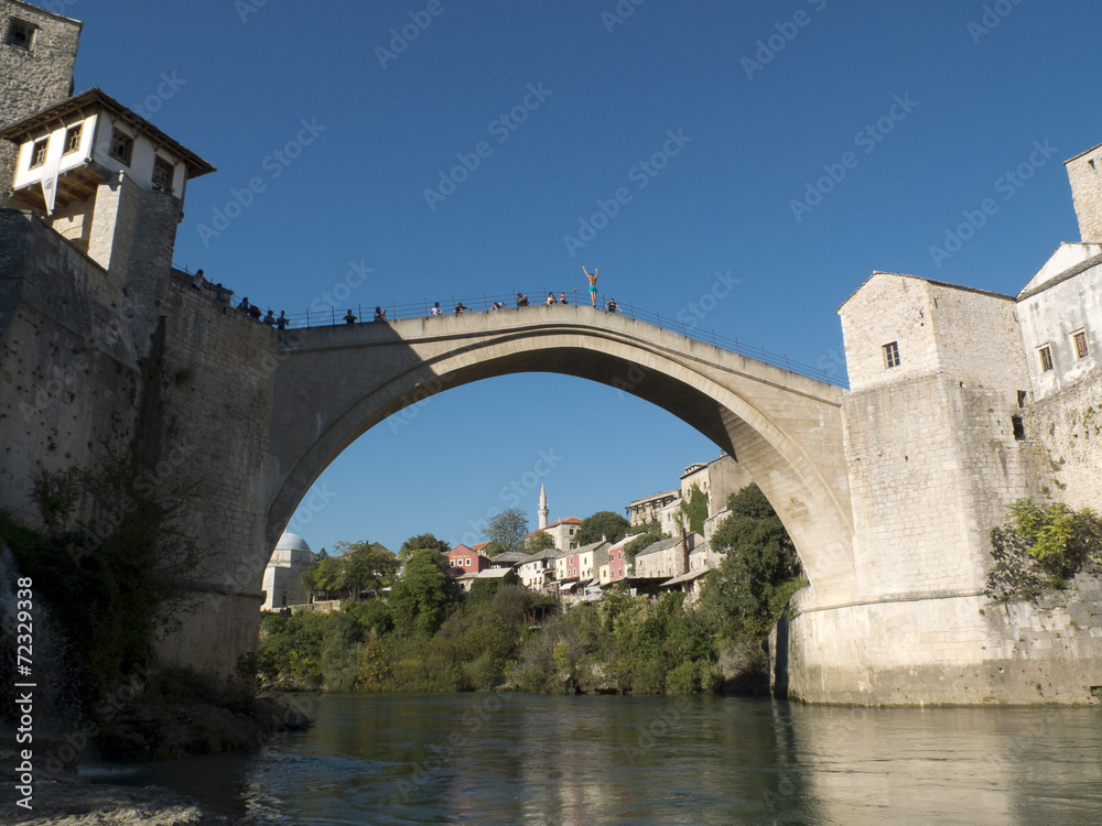 Plongeur, bras levés, sur le pont de Mostar en Bosnie.