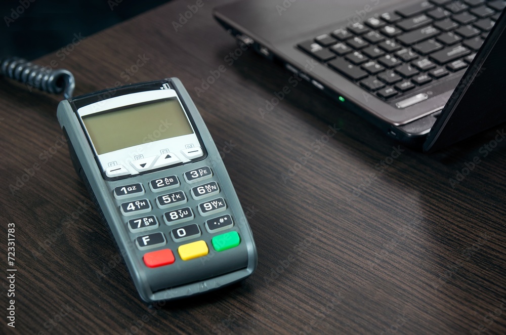Payment terminal in the office. Laptop in the background Payment terminal in the office. Laptop in the background