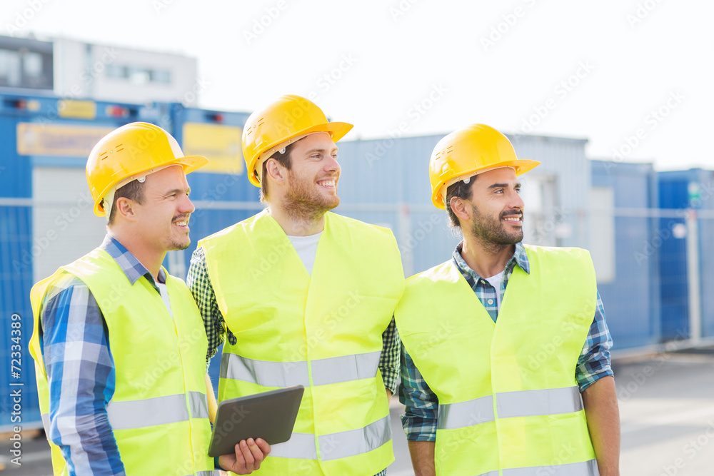 smiling builders in hardhats with tablet pc smiling builders in hardhats with tablet pc
