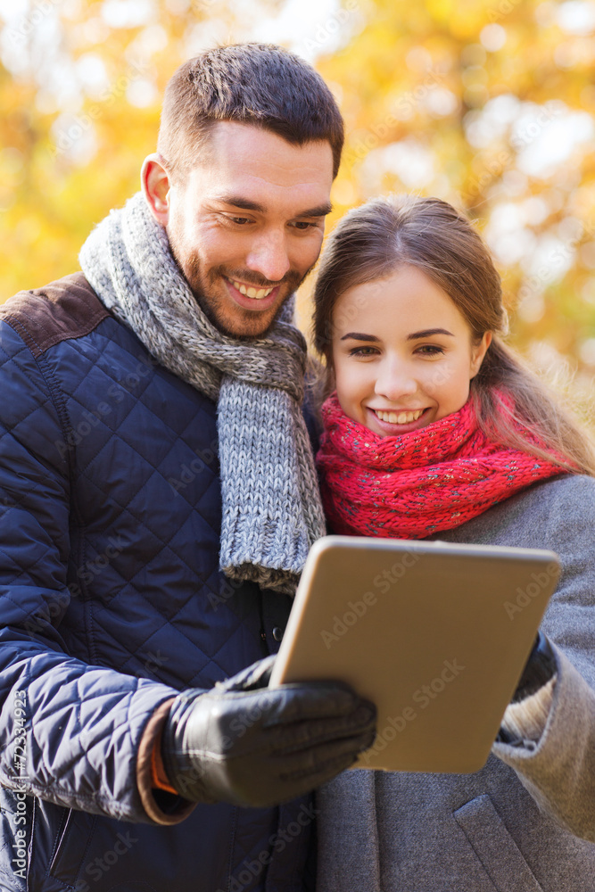 smiling couple with tablet pc in autumn park smiling couple with tablet pc in autumn park