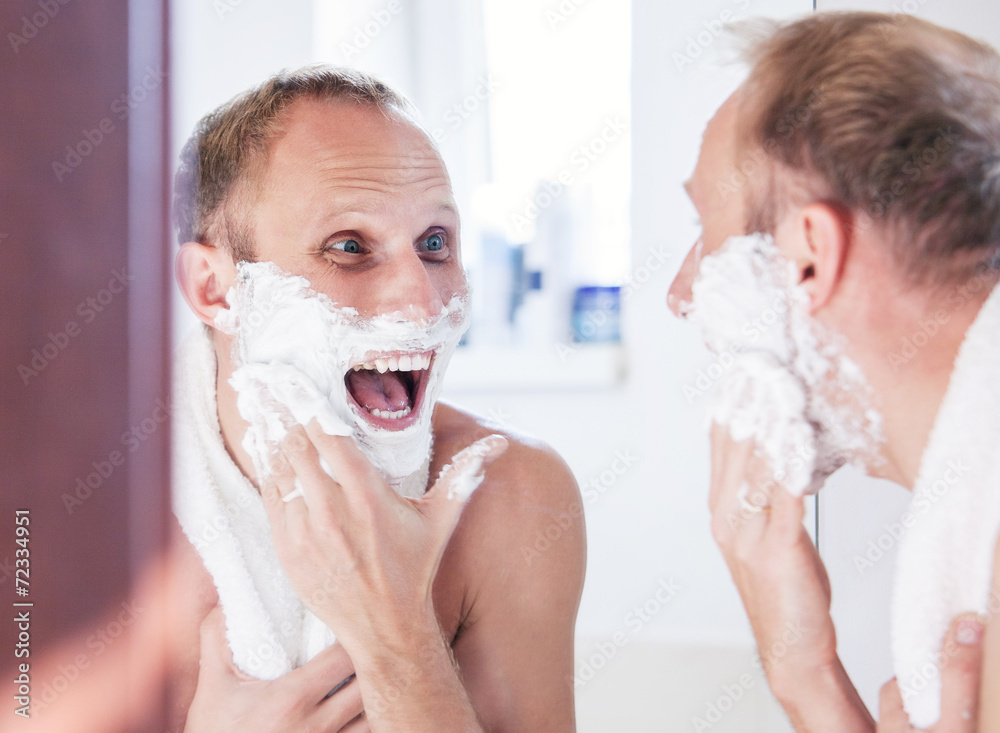 Happy man shaving in bathroom