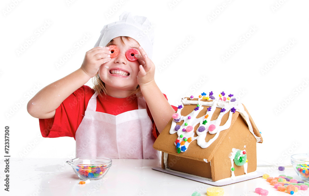 Girl Decorating a Gingerbread House with Candy Over her Eyes Girl Decorating a Gingerbread House with Candy Over her Eyes