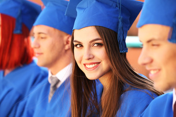 Graduate students wearing graduation hat and gown, outdoors