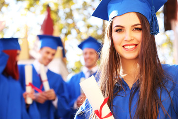 Graduate students wearing graduation hat and gown, outdoors