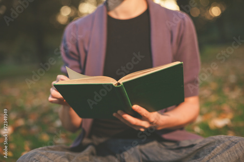 Woman reading in park at sunset