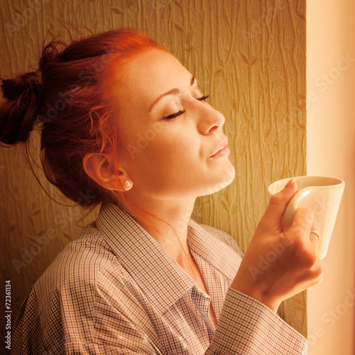beautiful woman early in morning with cup of coffee at window