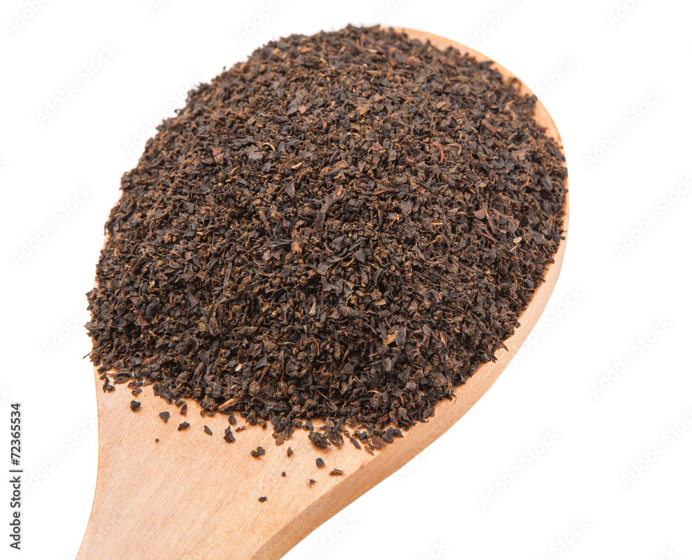 Dried, processed tea leaves in wooden spoon over white Dried, processed tea leaves in wooden spoon over white