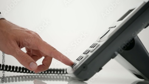 Male hand dialing telephone number and picking up a handset