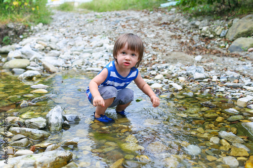 Fototapeta Naklejka Na Ścianę i Meble -  little child standing in flashy river