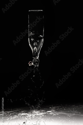Clear water spill from a glass bottle on black background on shi