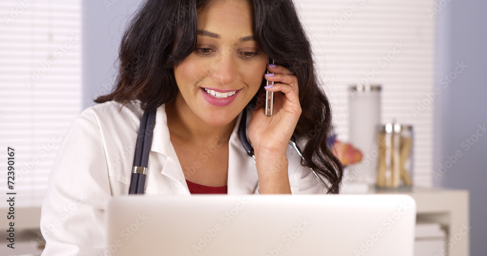 Mexican doctor talking on mobile phone and using laptop Mexican doctor talking on mobile phone and using laptop