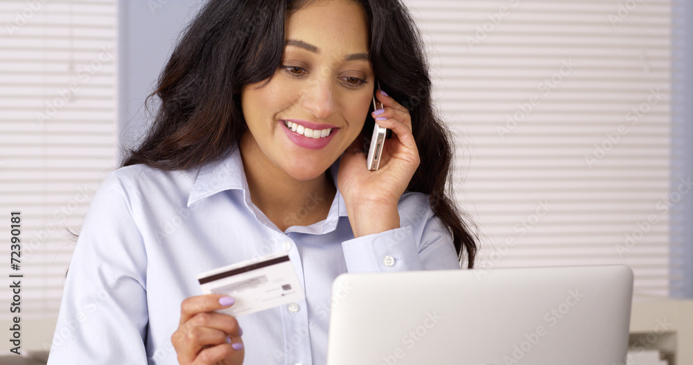 Mexican woman happily making purchase over the phone Mexican woman happily making purchase over the phone