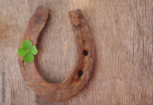 Old horse shoe,with clover leaf, on wooden background photo