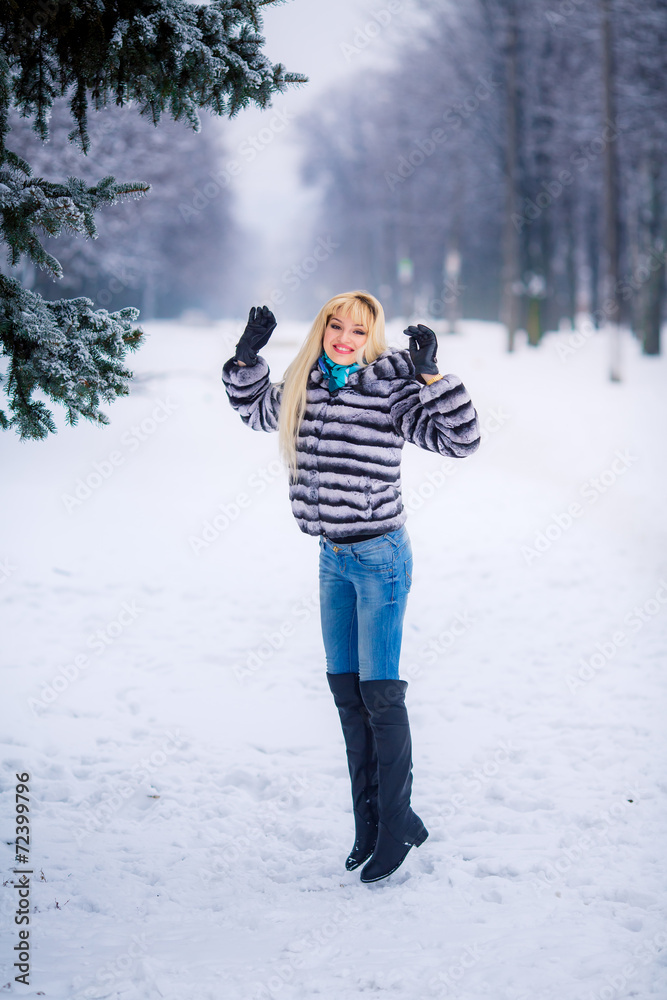 beautiful young blond woman in a winter park. Snow-covered trees
