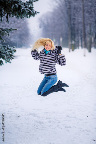 beautiful young blond woman in a winter park. Snow-covered trees