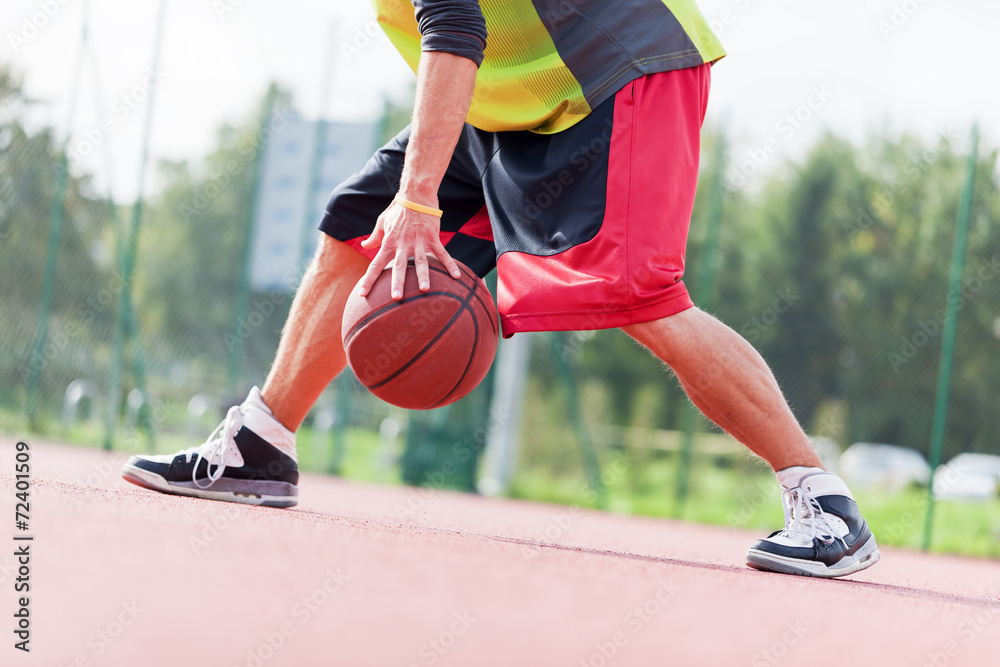 Young man on basketball court dribbling with ball