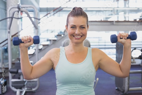 Fit brunette holding blue dumbbells