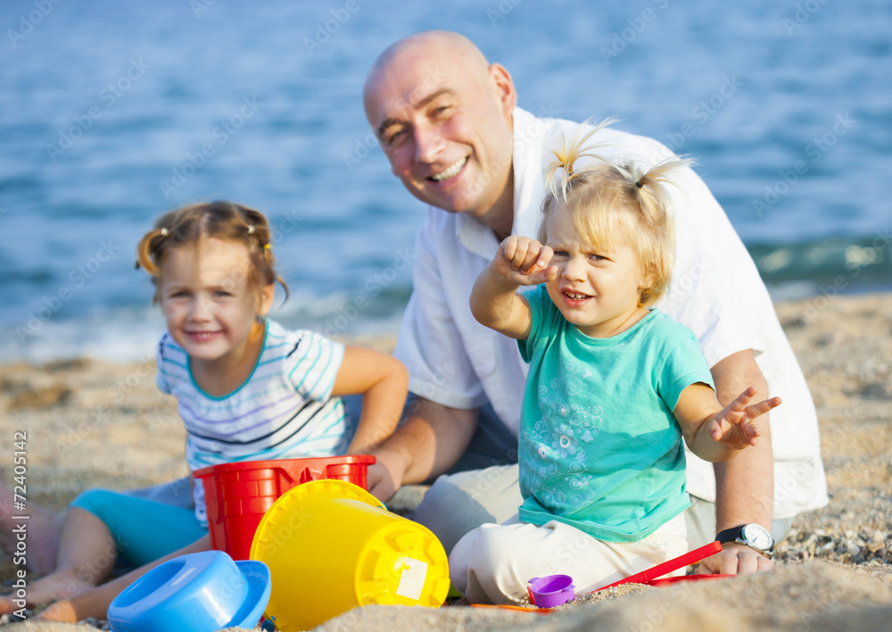 Fototapeta premium Dad and daughters on beach.