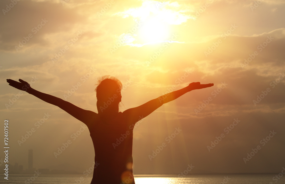 cheering woman open arms under the sunrise at seaside