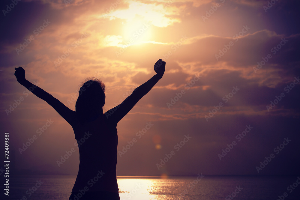 cheering woman open arms under the sunrise at seaside