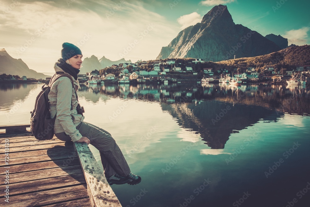 Woman sitting on a pier in Reine village, Norway Woman sitting on a pier in Reine village, Norway