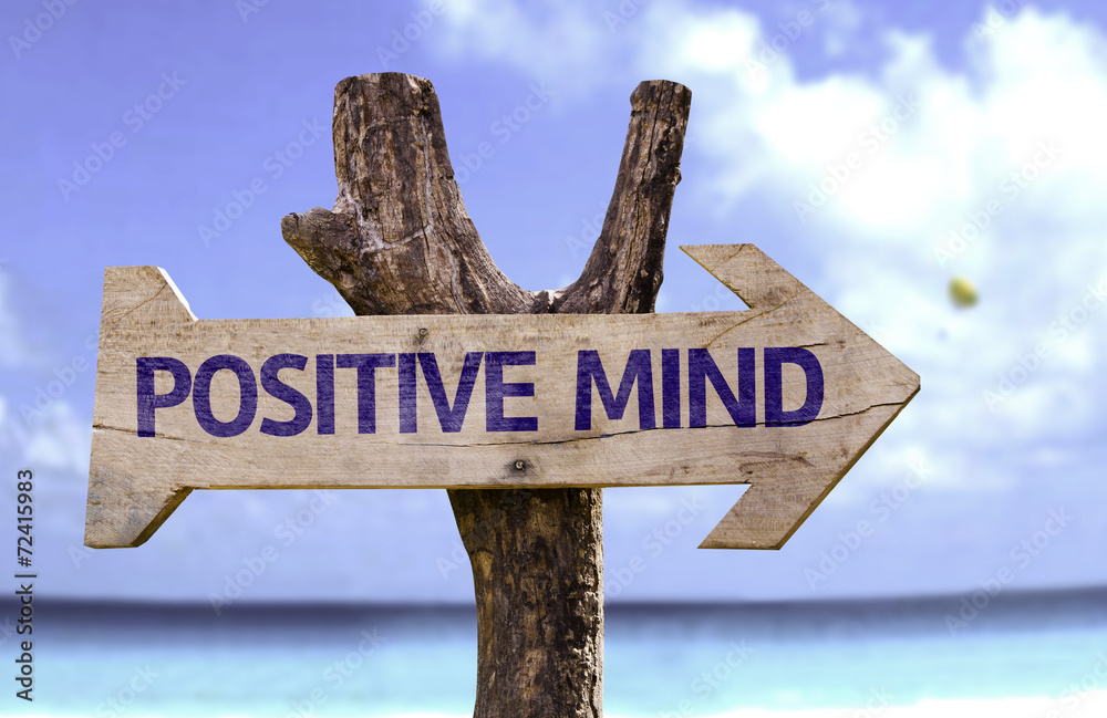 Positive Mind wooden sign with a beach on background