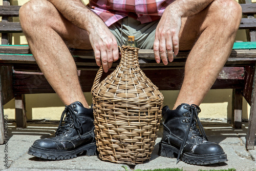 Fototapeta legs of man sitting on a bench with carboy