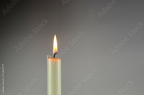 One white candle at grey background