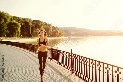 Running woman. Runner jogging in sunny bright light. Female fitn photo