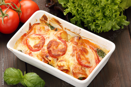 Cannelloni baked in a roasting pan on a wooden background