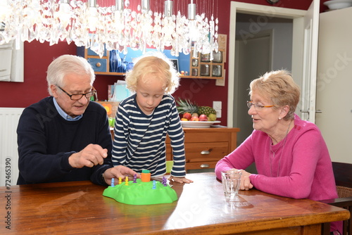 Großeltern spielen mit Enkelkind ein Gesellschaftsspiel