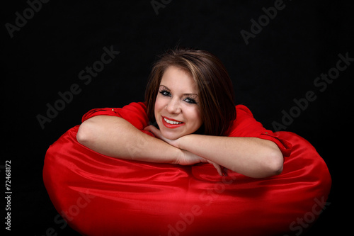 Uśmiechnięta dziewczyna na czerwonej poduszce.