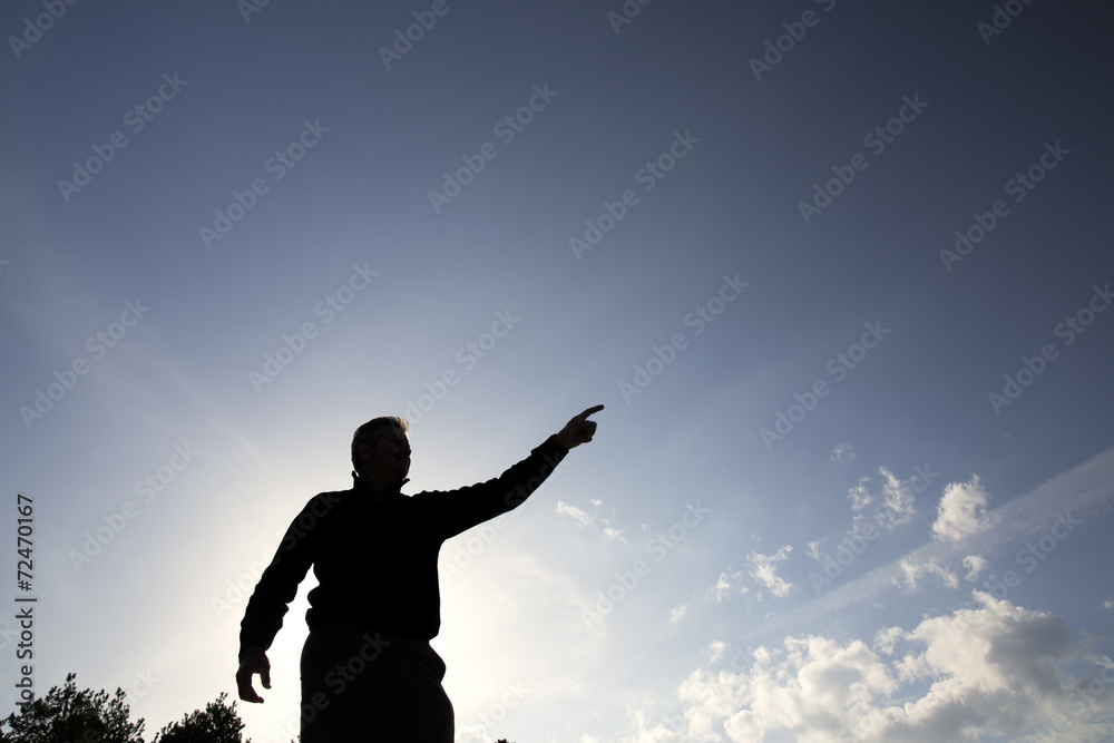 Backlit of a man pointing towards the horizon Backlit of a man pointing towards the horizon